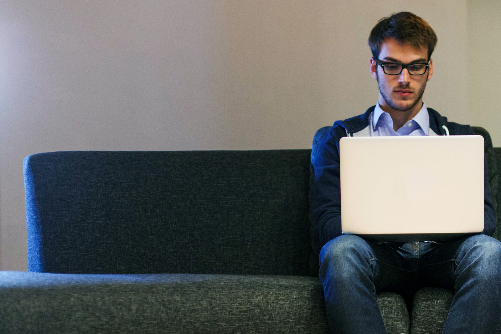 Man sitzt mit Notebook auf Couch Man sitzt mit Notebook auf Couch