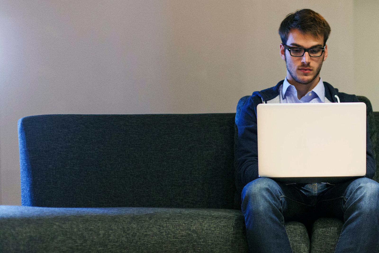 Man sitzt mit Notebook auf Couch